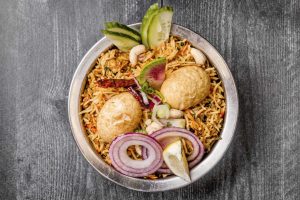 Egg Biryani with Slices of Onion, Cucumber and Lime Wedge
