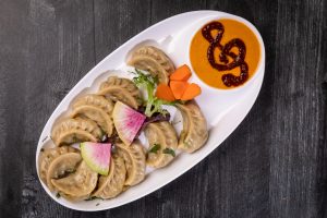Vegetable Momo on a white oval shaped plate with sauce.